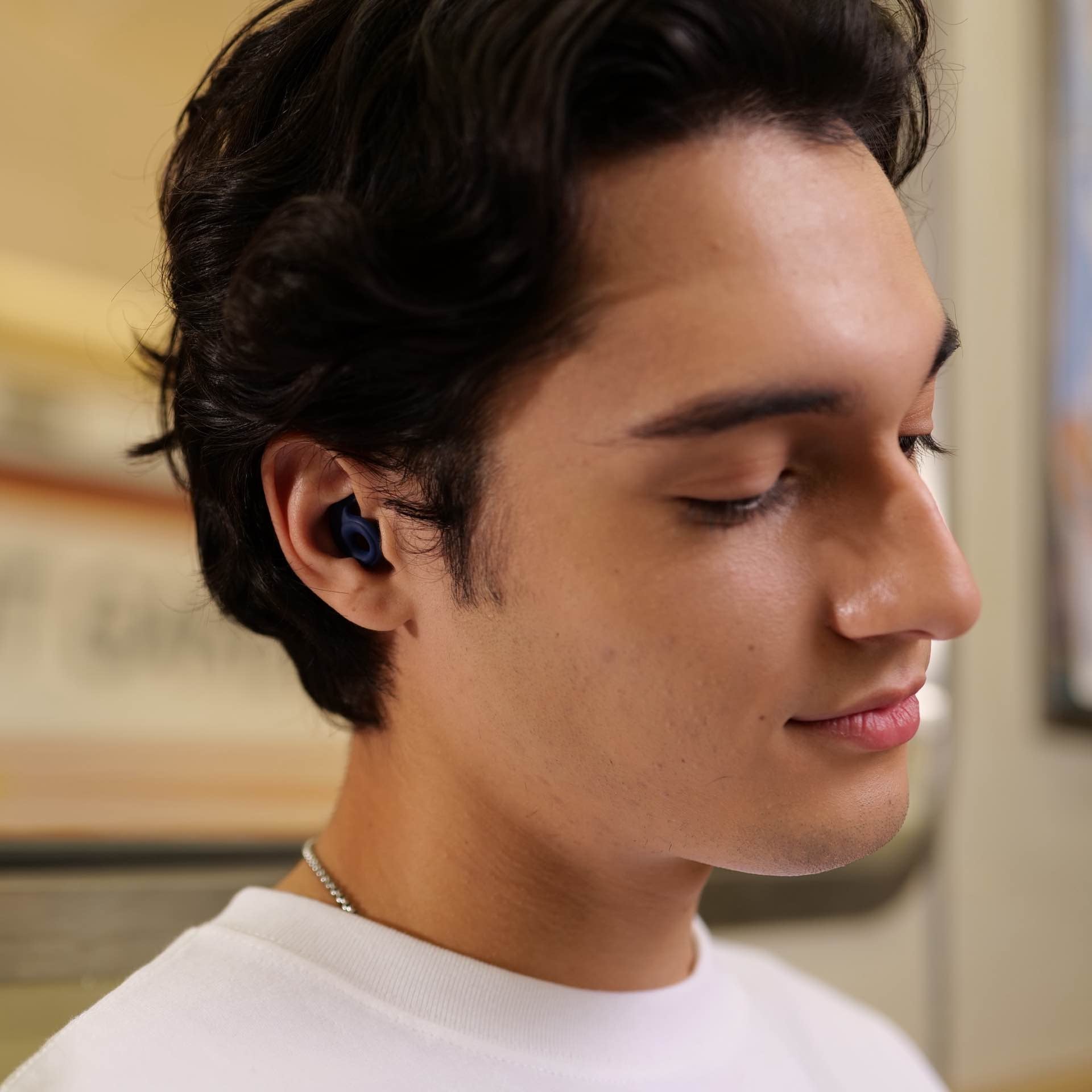 Person wearing noise canceling earplugs admist busy commute in a train