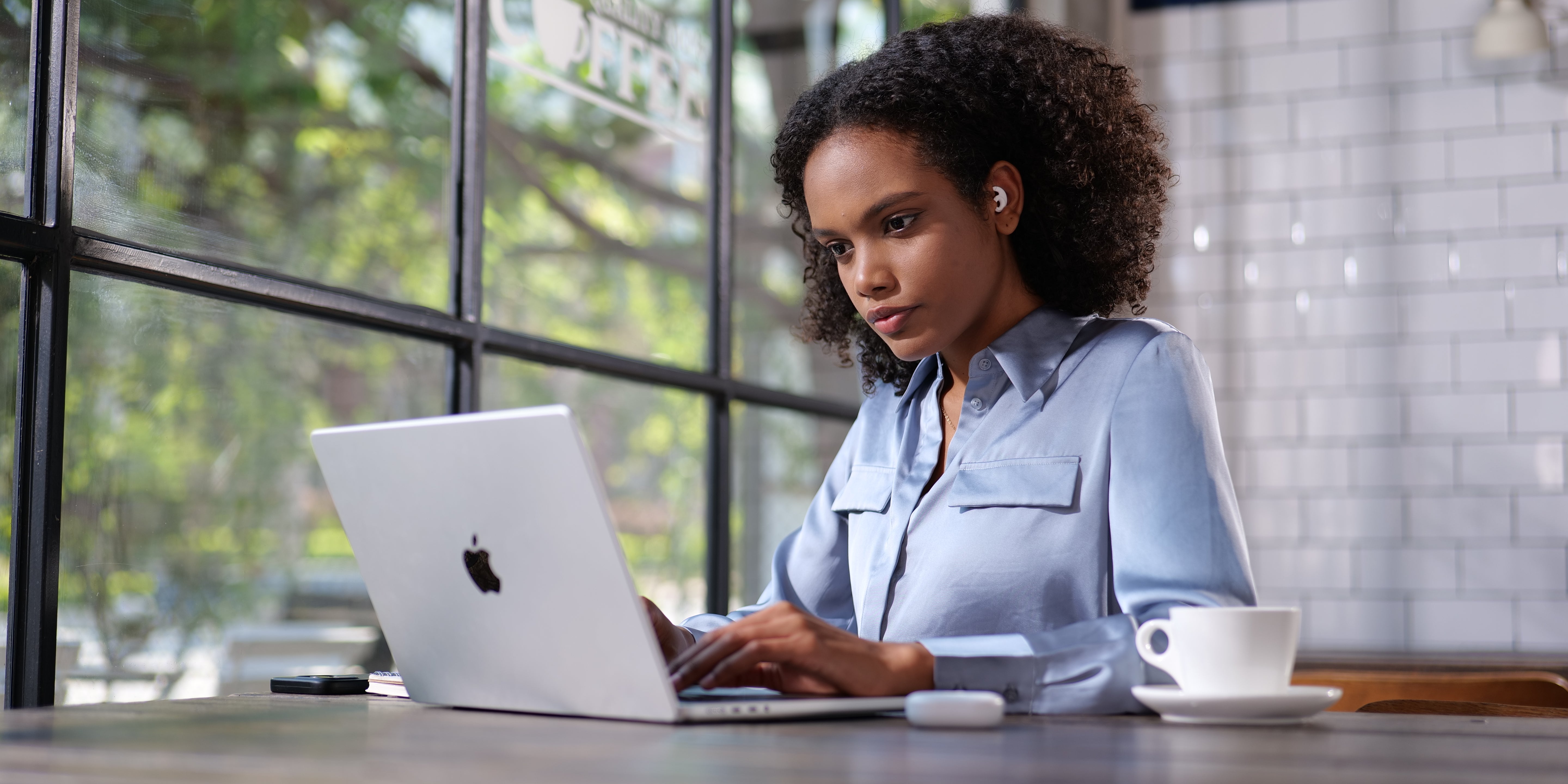 Woman is focused at work in a cafe with Welove Noise canceling Silicone Earplugs in her ears. ultra-comfy and snug-fit, block out noise and reduce distraction
