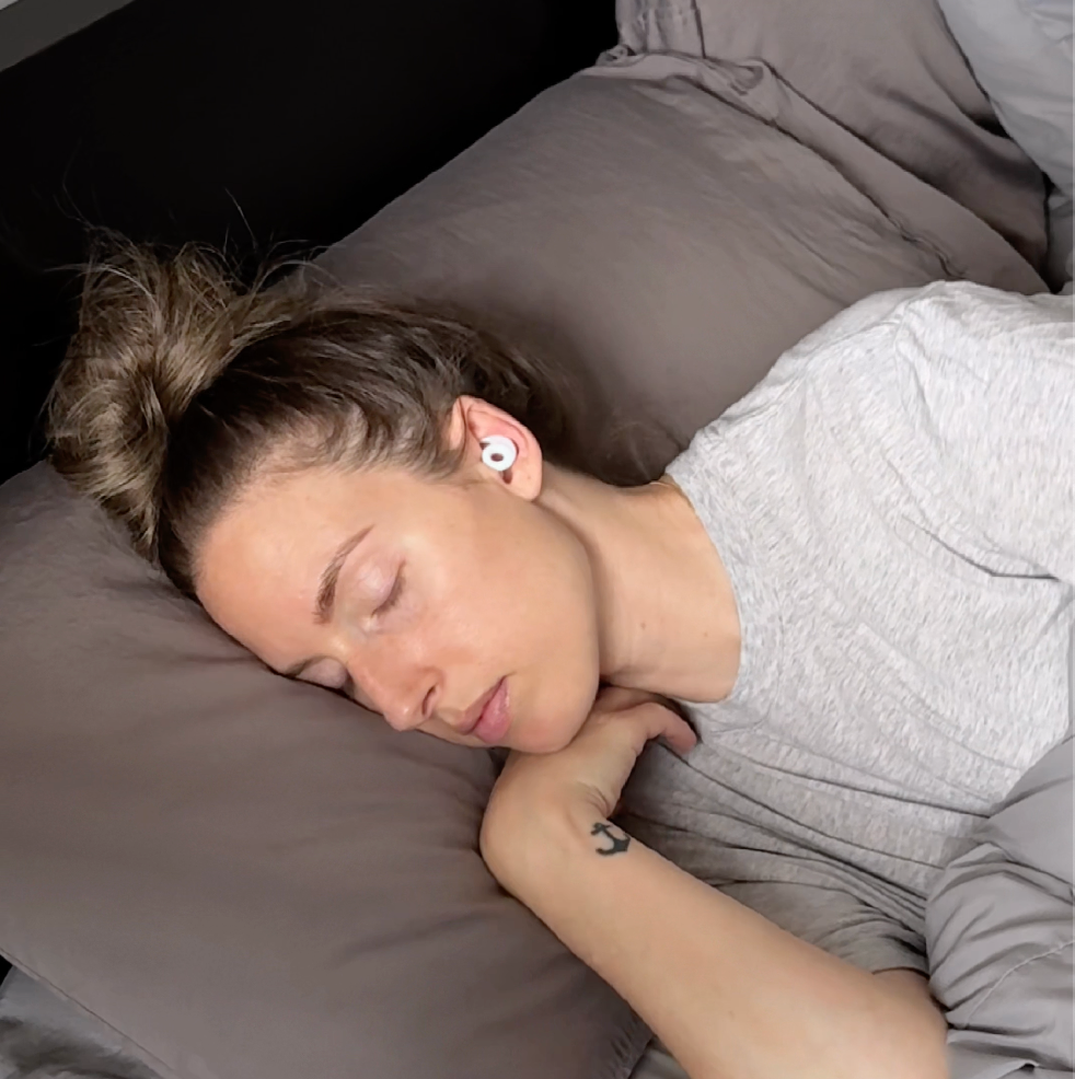 soft ergonomic earplugs worn by side sleeper in bed